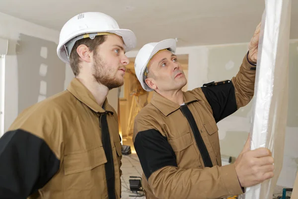 Construtor e aprendiz verifica a instalação correta no painel da porta da garagem — Fotografia de Stock