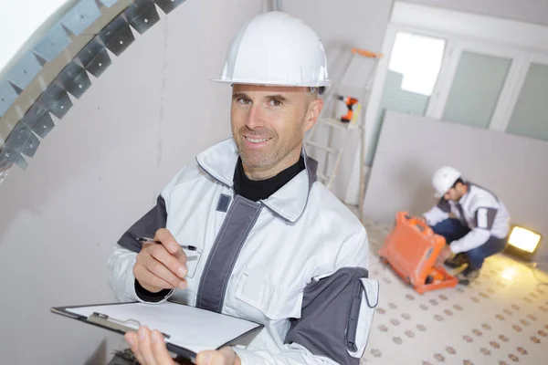Счастливый строитель проверяет буфер обмена внутри площадки — стоковое фото