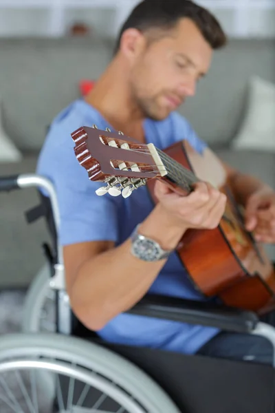 Uomo sulla sedia a rotelle che suona la chitarra — Foto Stock