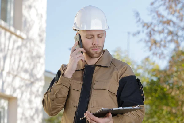 Інженер-будівельник говорить по телефону і тримає кишеню — стокове фото