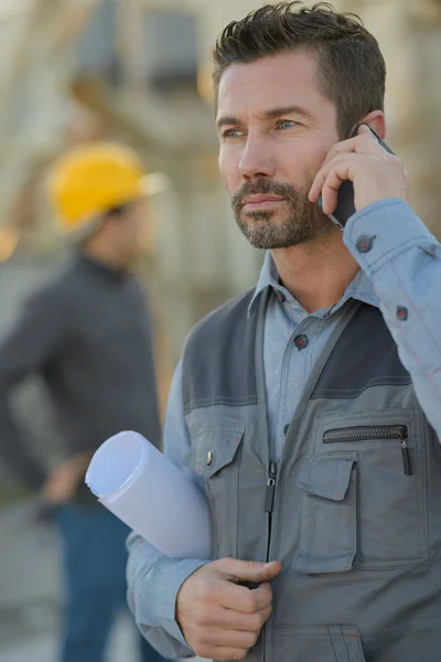 Инженер с мобильным телефоном на строительной площадке — стоковое фото