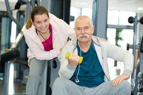 Personal trainer with senior man holding weights — Stock Photo, Image