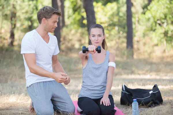 Personal trainer with lady holding dumbbell — Stock Photo, Image