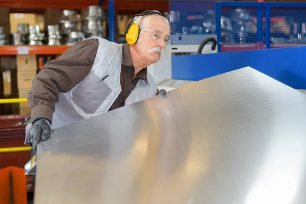 Senior man moving sheet metal — Stock Photo, Image