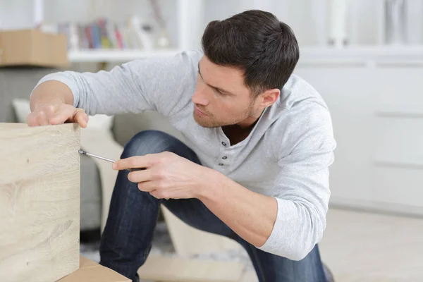 Man assembling furniture at home on the floor — Stock Photo, Image