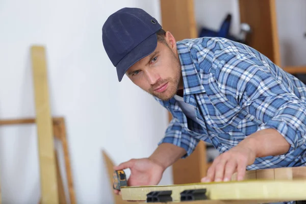 Bild eines jungen Mannes, der als Tischler und Messplatte arbeitet — Stockfoto