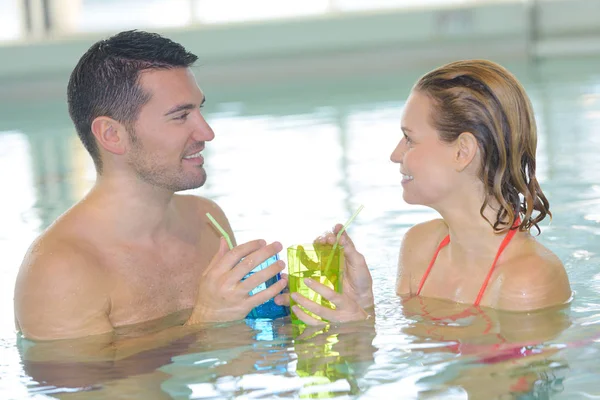 夫妇在游泳池里喝一杯鸡尾酒和放松 — 图库照片