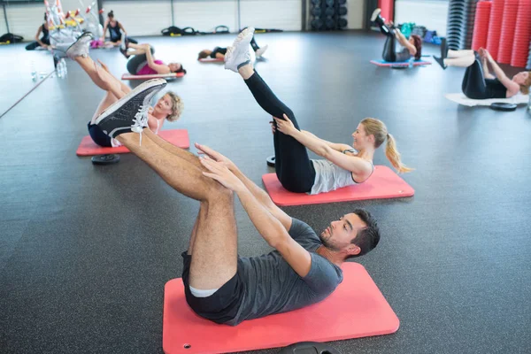 Portrait of active people doing leg stretching on exercise mat — Stock Photo, Image