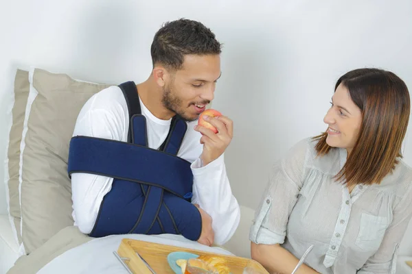 Homem ferido comendo maçã com a mão esquerda — Fotografia de Stock