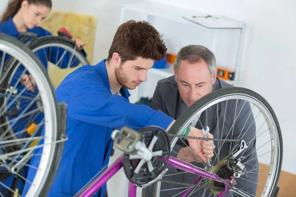 Trainee mekaniker reparerar cykeln — Stockfoto