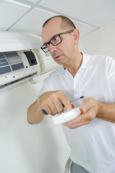 Técnico masculino examinando acondicionador de aire con multímetro — Foto de Stock