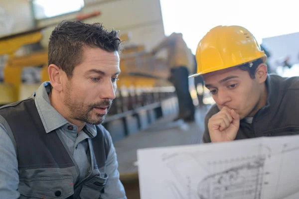 Superviseur masculin avec travailleur discuter sur les plans dans l'industrie — Photo