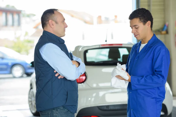 Young mechanic with client in garage — Stock Photo, Image