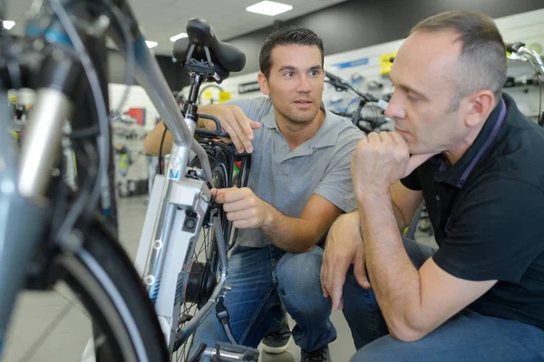 Ο άνθρωπος πελάτης και πωλητής συζητώντας ποδήλατο παραστάσεις στο κατάστημα ποδηλάτων — Φωτογραφία Αρχείου