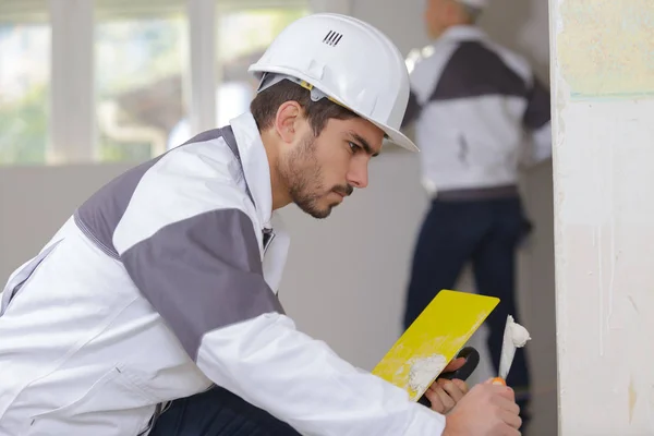 Jeune apprenti plâtrier travaillant sur mur intérieur — Photo