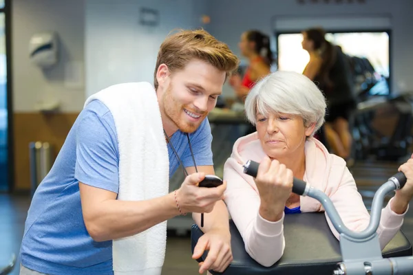 Personal trainer showing stopwatch time to senior client — Stock Photo, Image