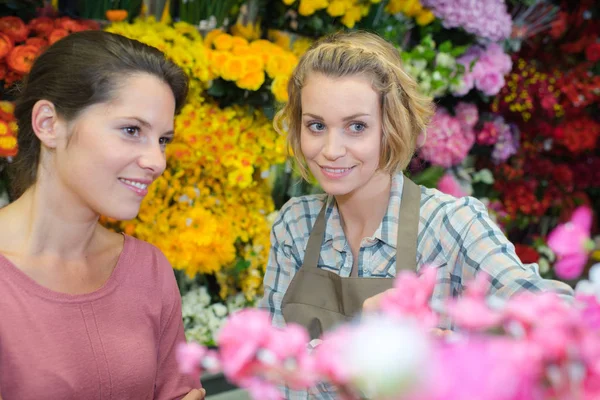 Vrolijke bloemist adviseren haar vrouwelijke klant — Stockfoto