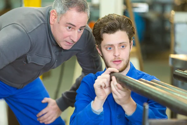 Aprendiz mostrando tubo de metal a supervisor — Foto de Stock