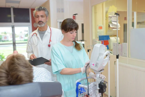 Лікар і медсестра взаємодіють з пацієнтом у лікарняній кімнаті — стокове фото