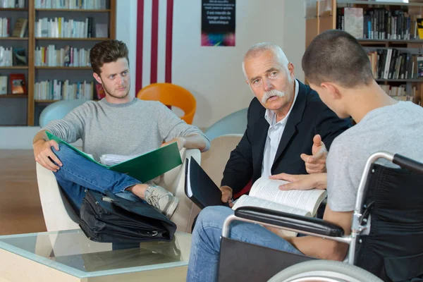 Handledare att prata med studenter, en i rullstol — Stockfoto