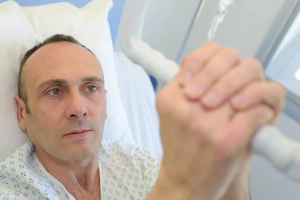 Patient im Krankenhausbett greift nach Hebezeug — Stockfoto