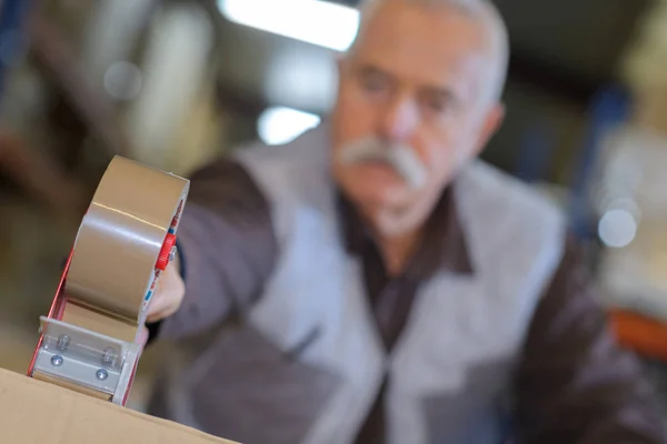 Close-up van tape dispenser, wordt gebruikt door senior man — Stockfoto