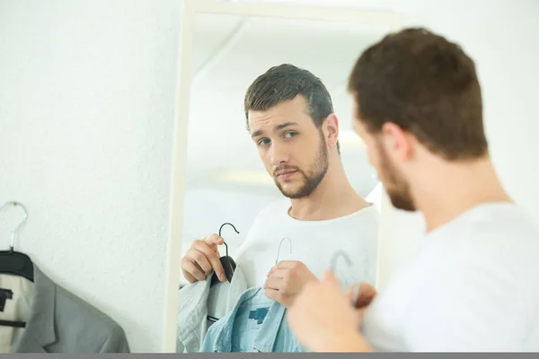 Hombre mirando en espejo comparando camisas —  Fotos de Stock