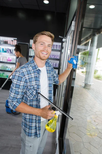 Feliz joven trabajador masculino ventana de limpieza con escobilla — Foto de Stock