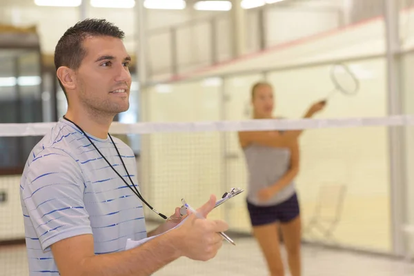 Leraar geven aantrekkelijke vrouw badminton les — Stockfoto