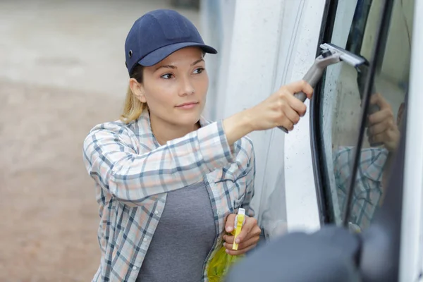 Una mujer limpiando una ventana de coche — Foto de Stock