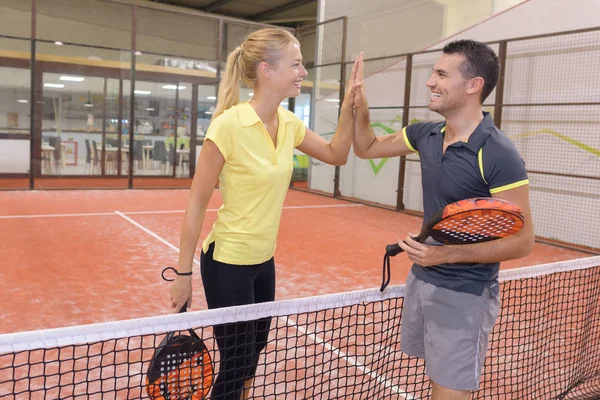 Feliz pareja jugando tenis pista de tenis cubierta — Foto de Stock