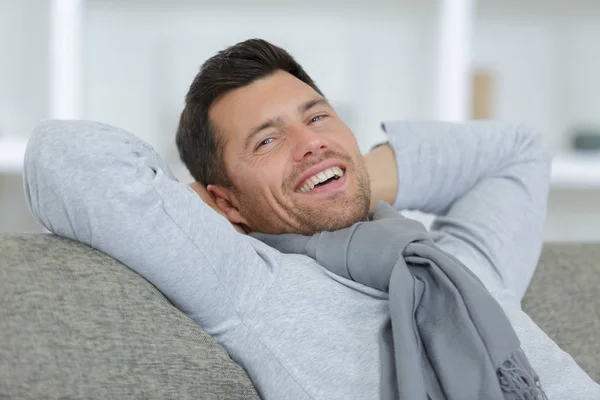 Mann lächelt auf Sofa — Stockfoto