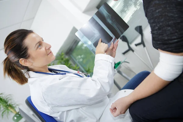 Doutor mostrando paciente um raio-x de seu braço ferido — Fotografia de Stock