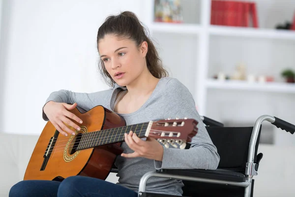 Jovem mulher na cadeira de rodas tocando guitarra — Fotografia de Stock