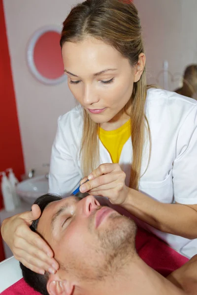 Kosmetolog plockning mannen s ögonbryn — Stockfoto