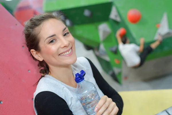 Woman holding bottle of water in sports center — Stock Photo, Image