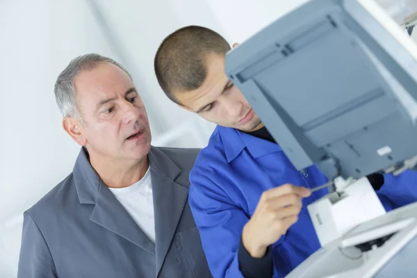 Supervisore guardando il giovane tecnico al lavoro — Foto Stock