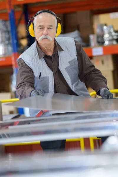 Hombre mayor trabajando con orejeras — Foto de Stock