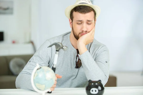 Hombre sosteniendo martillo mirando desanimadamente a Piggybank — Foto de Stock