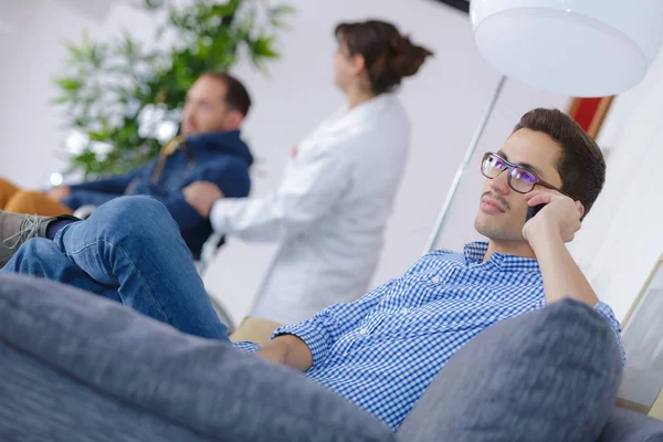 Mann mit Handy, Krankenschwester schubst Mann im Rollstuhl im Hintergrund — Stockfoto