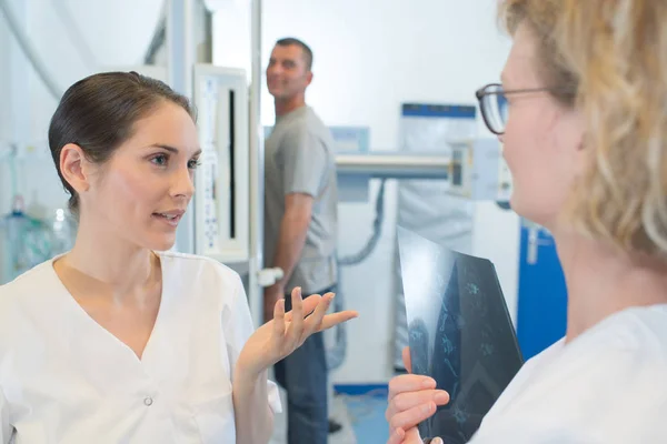 Trabajadores médicos hablando mientras el paciente espera la radiografía — Foto de Stock