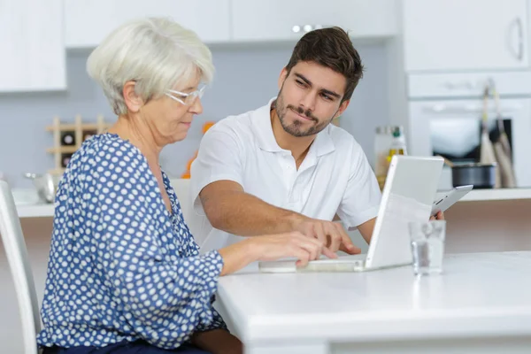 Giovane uomo mostrando signora anziana come utilizzare il computer portatile — Foto Stock