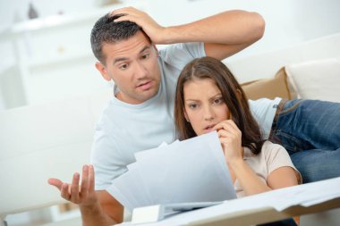 Young couple looking in shock at bills clipart