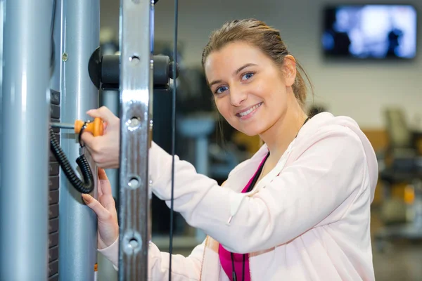 Kvinna chaging position stift på vikter maskin — Stockfoto