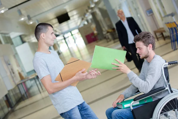 Estudiante discapacitado pasando archivo a amigo — Foto de Stock