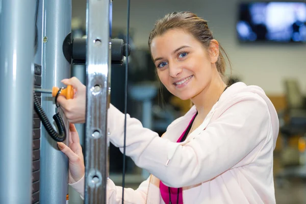 Donna aggiungendo pesi su una macchina palestra — Foto Stock