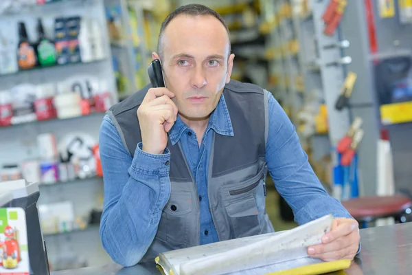 Man looking through stock sheets and talking on telephone — Stock Photo, Image