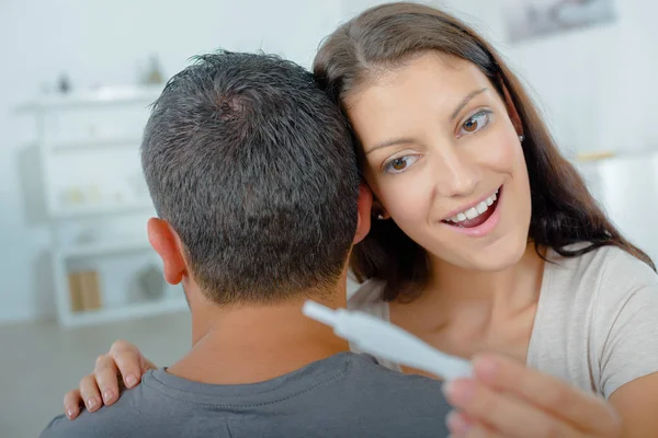 Женщина смотрит на тест на беременность через плечо партнера — стоковое фото