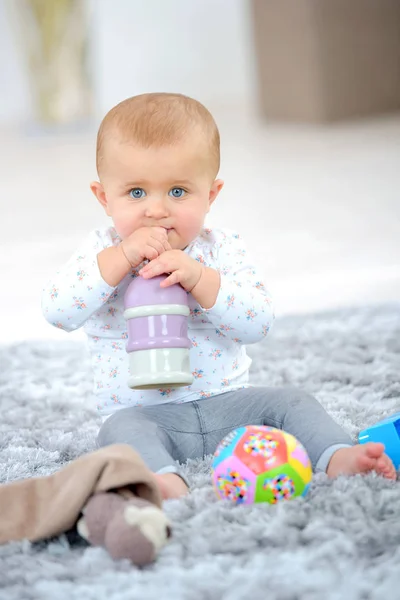 Девочка на ковре играет с игрушками — стоковое фото