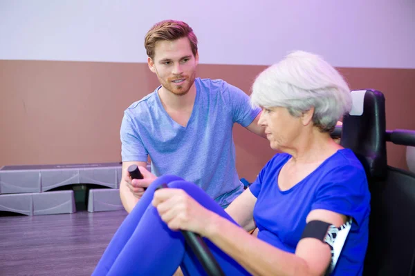 Fyzioterapeut, pomáhat starší žena použití výkon zařízení — Stock fotografie